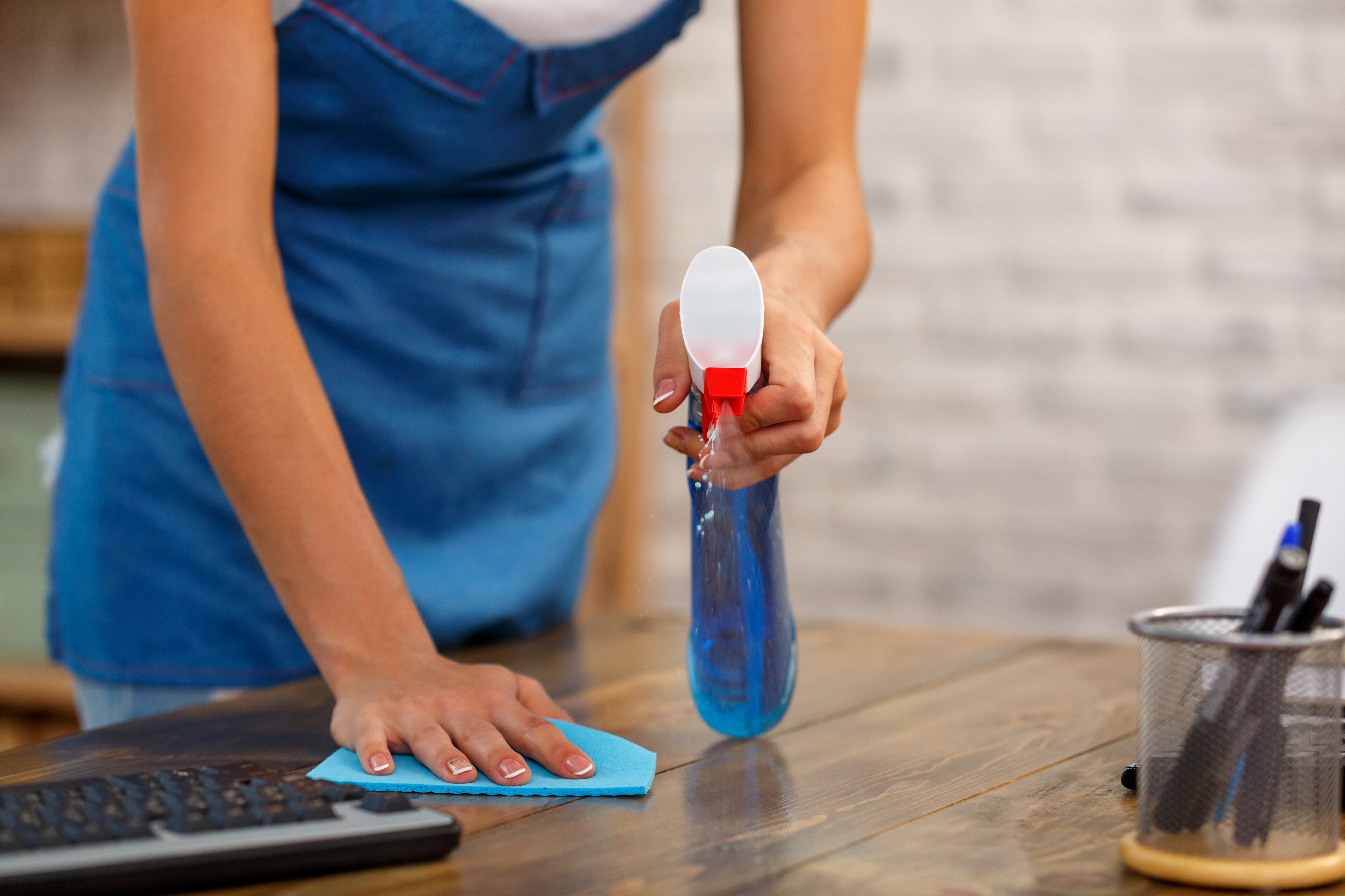 Person rengør træbord med sprayflaske